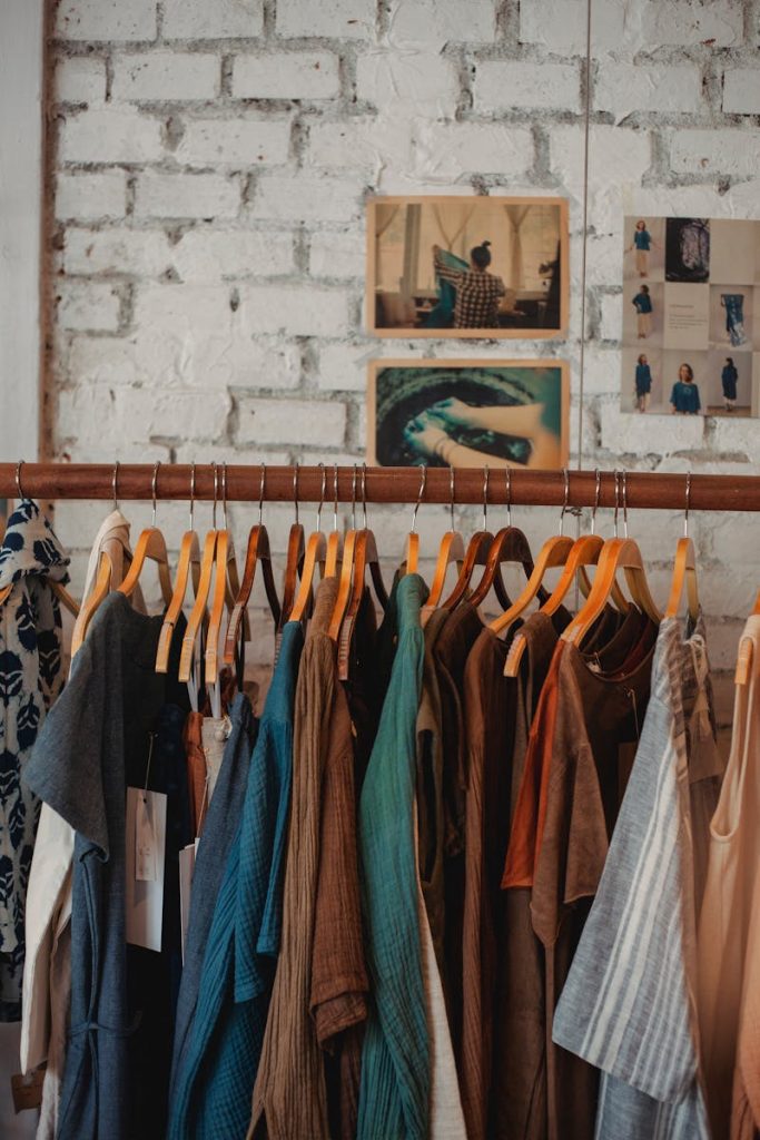Photo by Sam Lion Colorful assortment of clothes on wooden hangers in a trendy boutique.